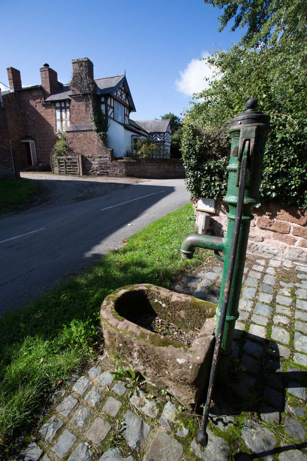 Village of Churton, Cheshire, England. Picturesque view of a restored water pump on Pump Lane.